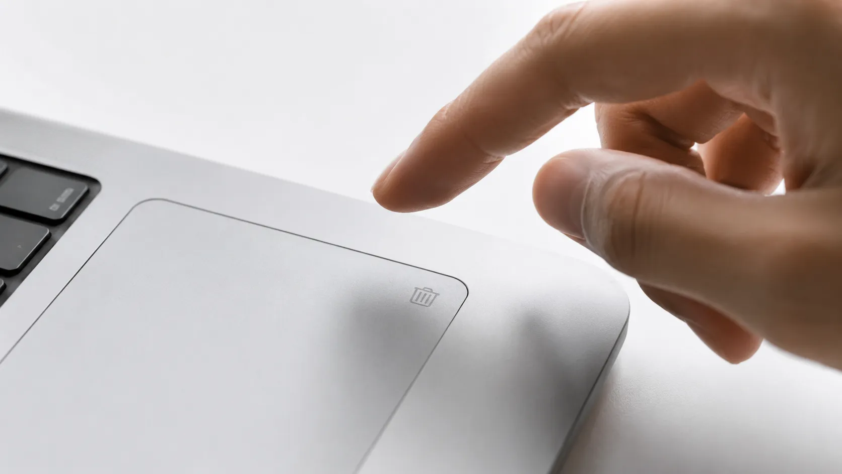 Hand near a trackpad trash icon symbolizing uninstalling apps with the best mac cleaner