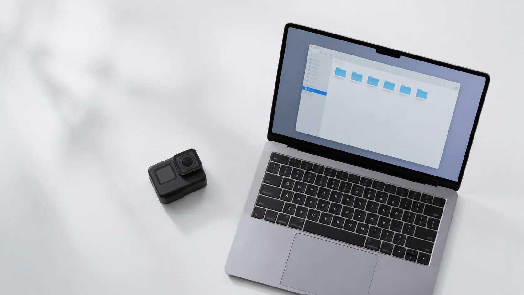 GoPro camera beside MacBook with Finder DCIM folder open for drag-and-drop video import on Mac