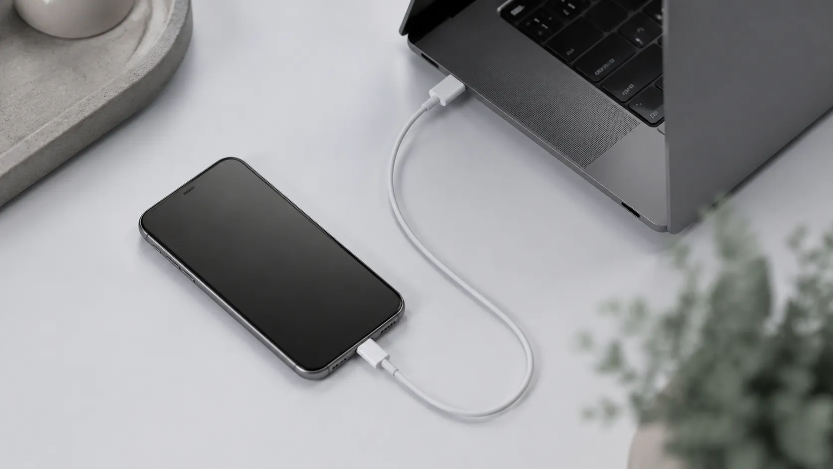 USB-C cable connecting an iPhone to a MacBook for wired mirror iPhone to Mac setup