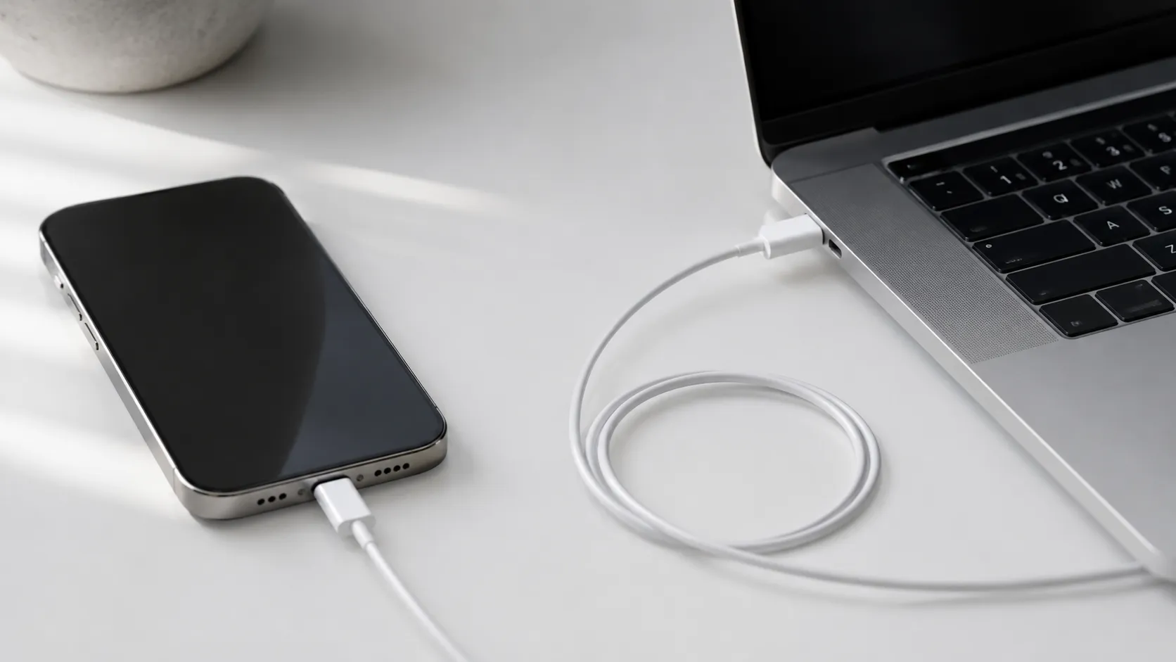 iPhone connected to a MacBook with a USB-C cable, ready to transfer photos to the Mac